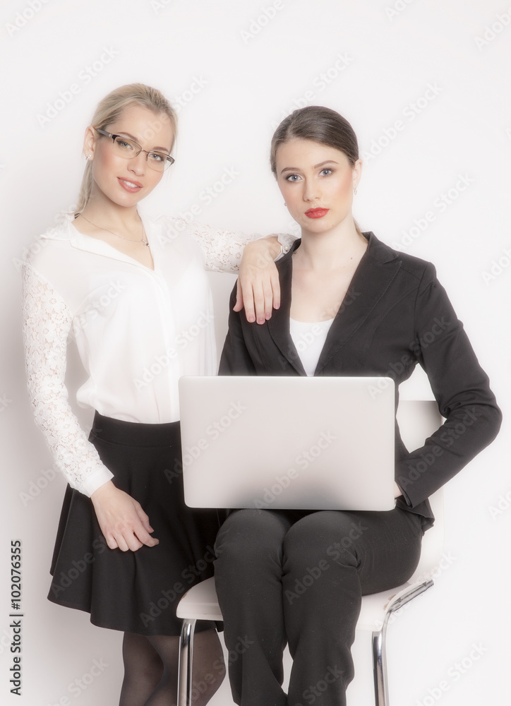 Two business woman on a white background. The business girl looks at the monitor and working. Two business woman on a white background. The business girl looks at the monitor and working.