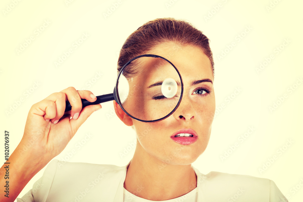 Businesswoman looking into a magnifier and have a big eye Businesswoman looking into a magnifier and have a big eye