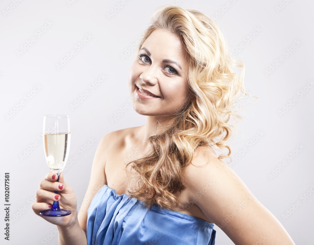 Beautiful curly-haired blond with a glass of champagne. A young woman in blue evening dress. Smiling girl on a gray background
Beautiful curly-haired blond with a glass of champagne. A young woman in blue evening dress. Smiling girl on a gray background