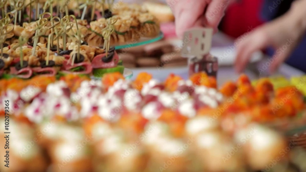 Close up of many canapes set  and snacks on  table and hands picking them. Buffet dinner or stand up party. Handheld shot, rack focus.