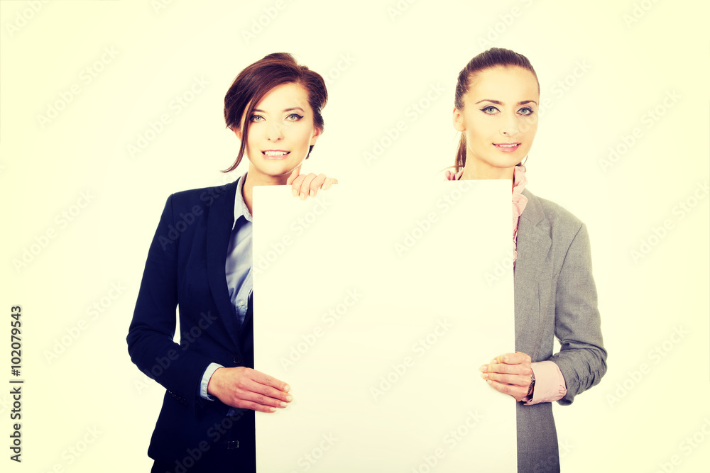 Two businesswomen carrying a big white board. Two businesswomen carrying a big white board.