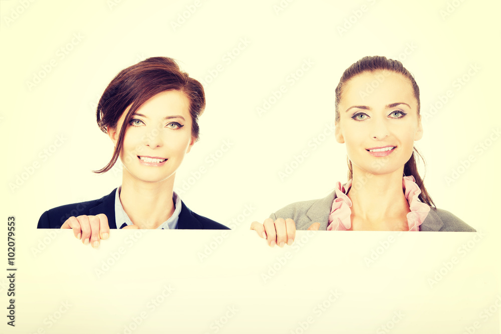 Two businesswomen carrying a big white board. Two businesswomen carrying a big white board.