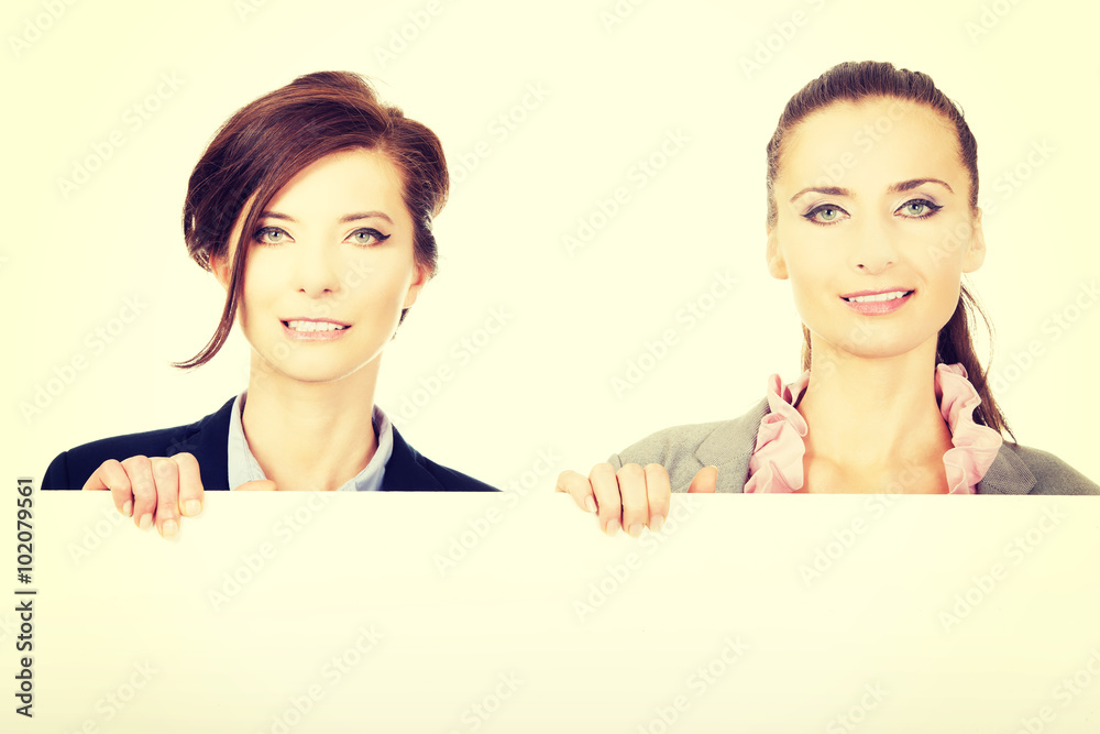 Two businesswomen carrying a big white board. Two businesswomen carrying a big white board.