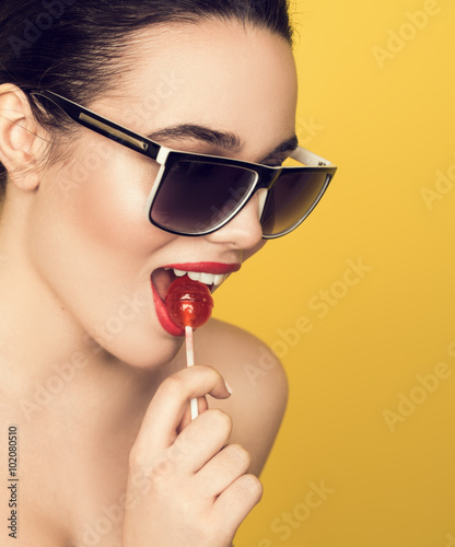 Brunette girl studio portrait licking candy