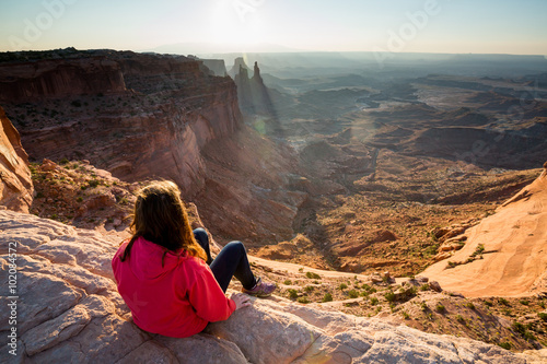 Obraz na płótnie Girl sitting at the Mesa Arch at sunrise, Canyonlands w salonie