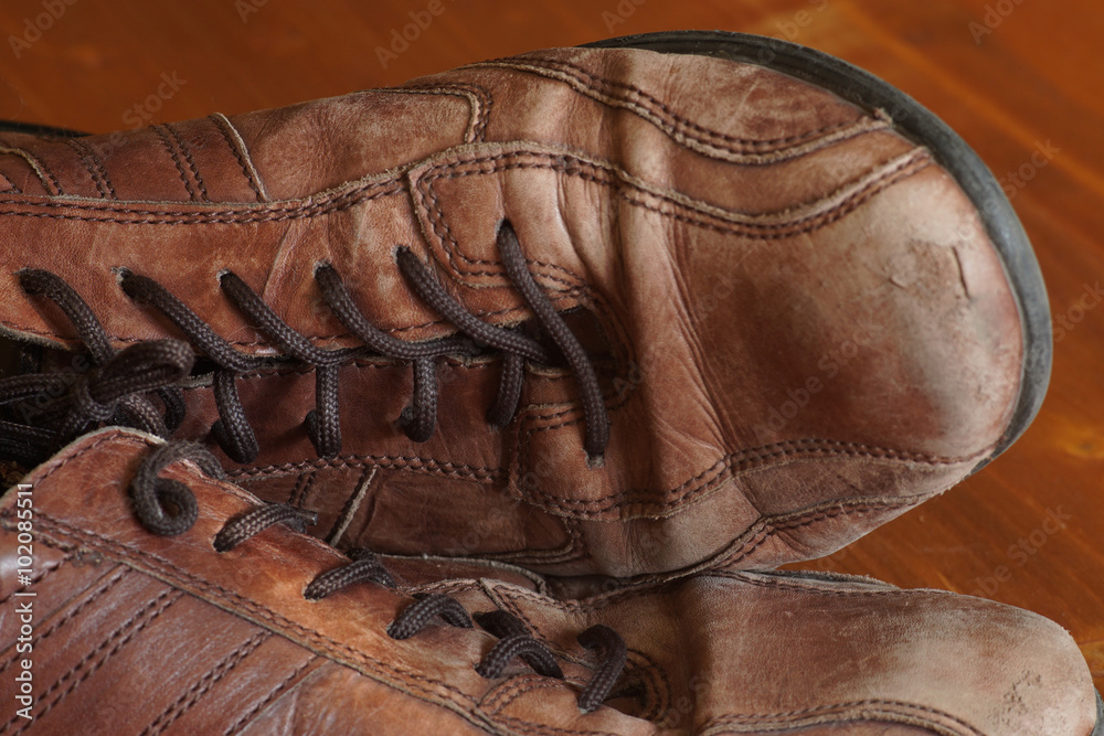 Part of old shoes with laces on wooden floor Part of old shoes with laces on wooden floor