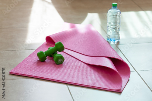 Two  dumbbells with mineral water on  yoga mat photo