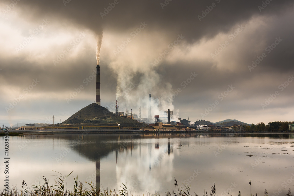 Silhouette of factory with chimneys and heavy smoke
