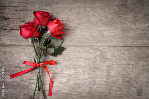 Valentines day background with red rose and ribbon on wooden.  Dual tone.