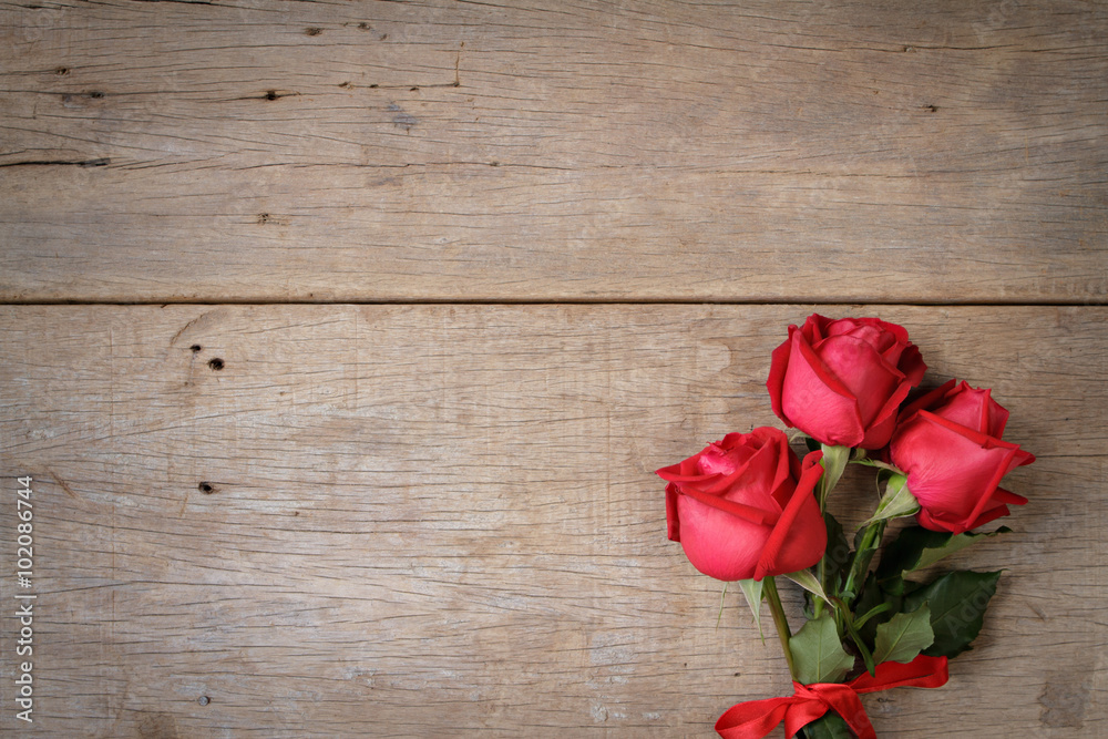 Valentines day background with red rose and ribbon on wooden.