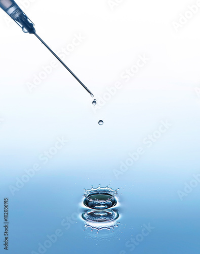 The syringe needle on the blue water background with splash and drops