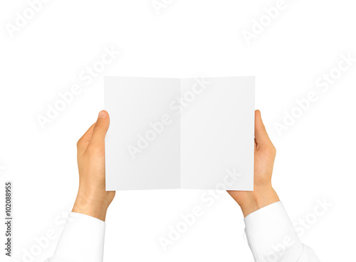 Hand in white shirt sleeve holding blank booklet card in the hand.