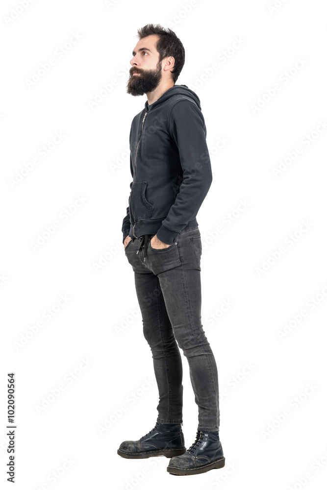 Side view of bearded punker or hipster with hands in pockets looking up. Full body length portrait isolated over white studio background. Side view of bearded punker or hipster with hands in pockets looking up. Full body length portrait isolated over white studio background.