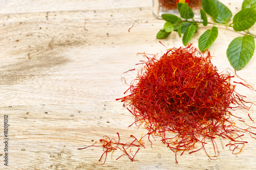 Red saffron with fresh mint on teak wood table top, copy space photo