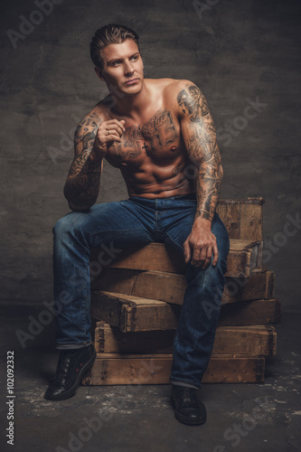 Shirtless muscular man with tattooes on his body.