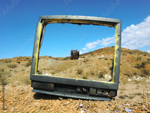 Empty television shell on desert floor with abandoned silver mine behind - landscape photo