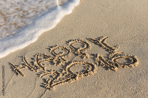 Inscription Happy 2016 on sandy beach with wave's foam
