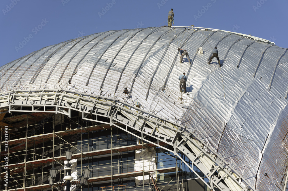 Construction workers-roofers, tied with ropes for protection work on the roof of a new building - the dome of the new building of the Philharmonic Orchestra in Skopje - Macedonia under construction 3