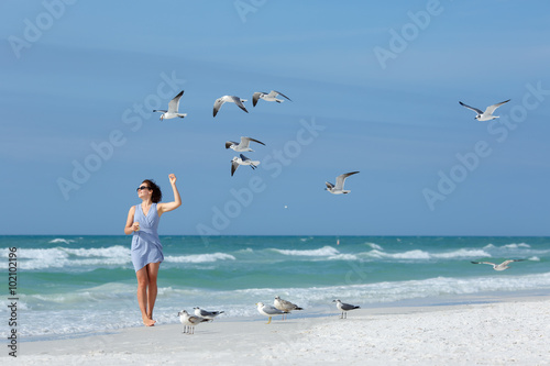 Young woman feeding seagulls on tropical beach, Florida photo