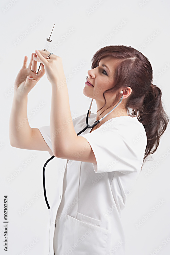 Beautiful young lady doctor with stethoscope and syringe preparing to make injection. Beautiful young lady doctor with stethoscope and syringe preparing to make injection.