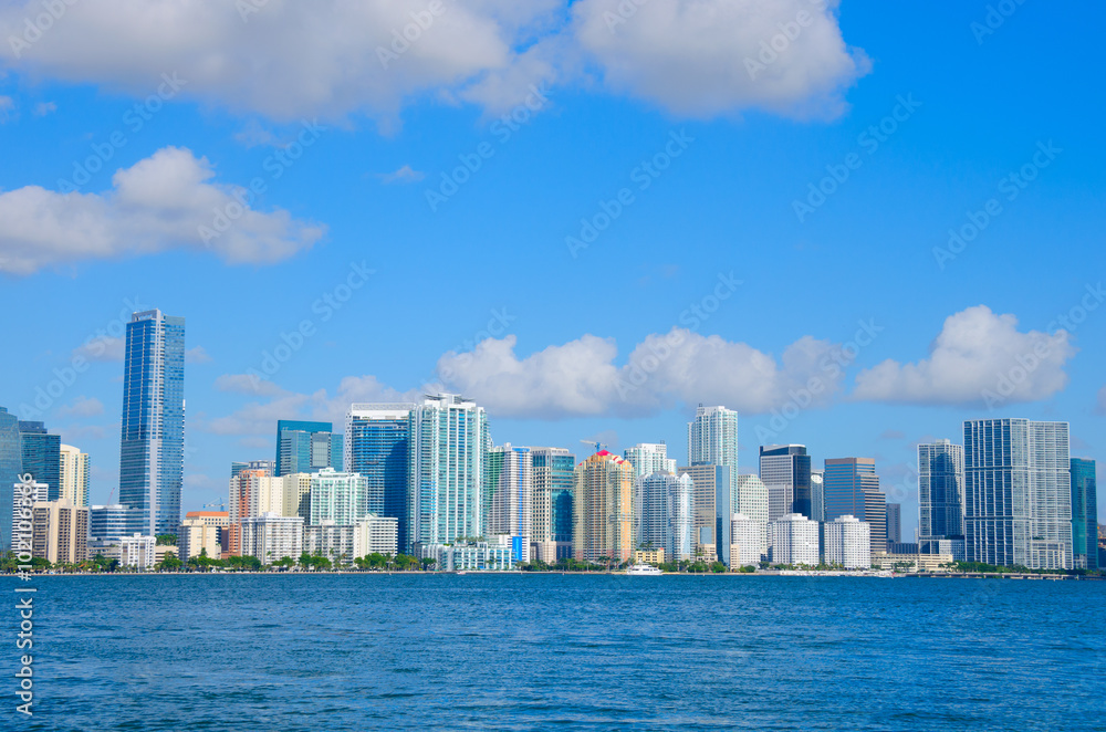 Colorful photo of the Miami skyline as viewed off of the coastline in Biscayne Bay, Florida on a blue sky sunny morning.