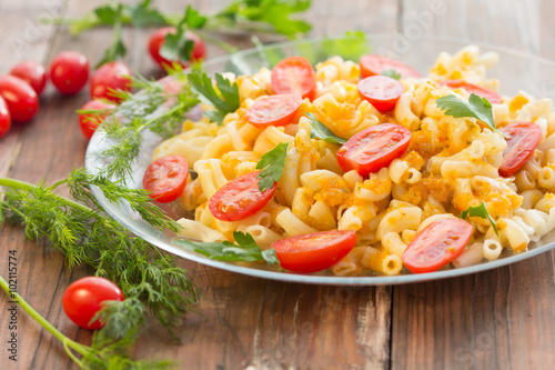 Macaroni pasta in vegetable sauce with fresh tomatoes and parsley on wooden dark background. Vegetarian o healthy food concept