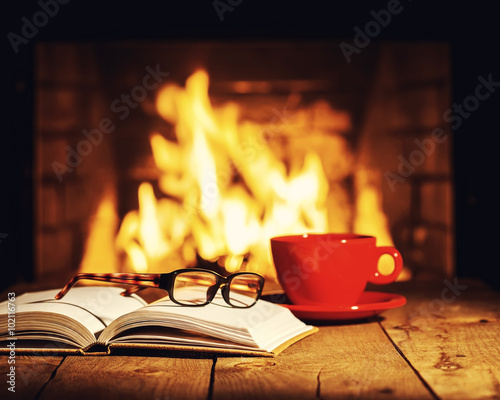 Fotografia Red cup of coffee or tea, glasses and old book on wooden table n