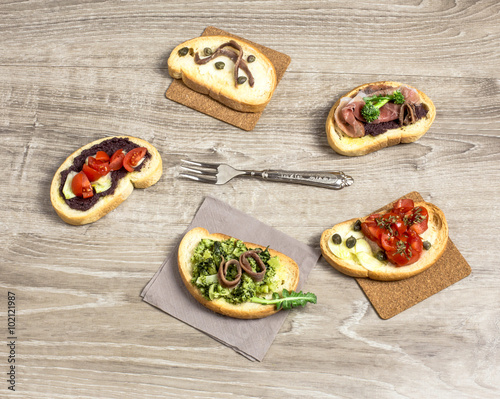 five bruschettas over wooden table with vintage fork