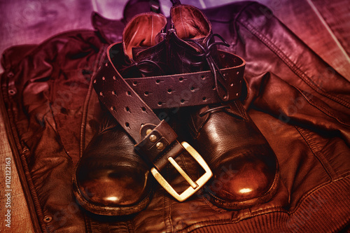 men's clothing and accessories in a still-life - leather jacket, high leather footwear and a leather belt with buckle