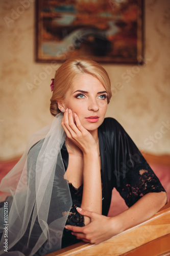 Gorgeous blonde bride in robe posing and preparing for the wedding ceremony face in a room