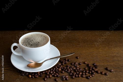 Cup of coffee with beans on a wooden table