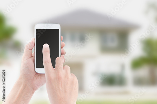 Hands holding and touch screen of smart phone on house backgroun