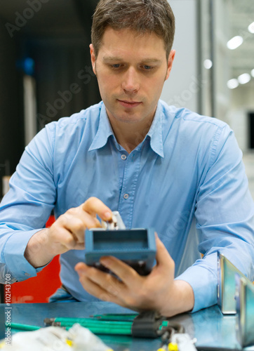 Handsome worker assembling electronic components at the factory.