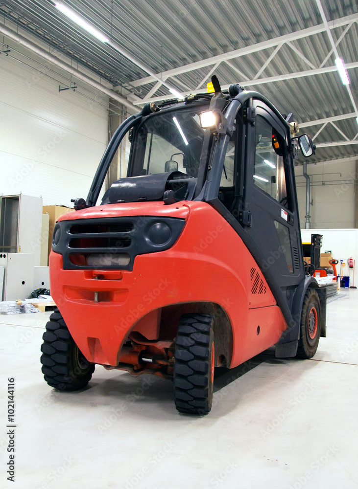Orange forklift loader in the modern warehouse. Orange forklift loader in the modern warehouse.