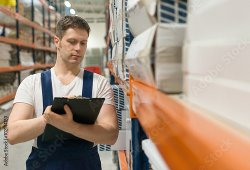 Supervisor with clipboard checking barcode at the warehouse.