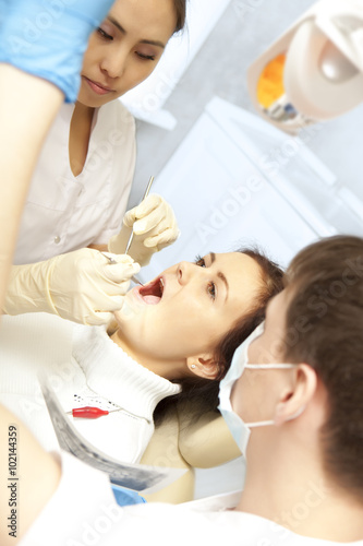 Young woman keeping her mouth open while dentist examining it