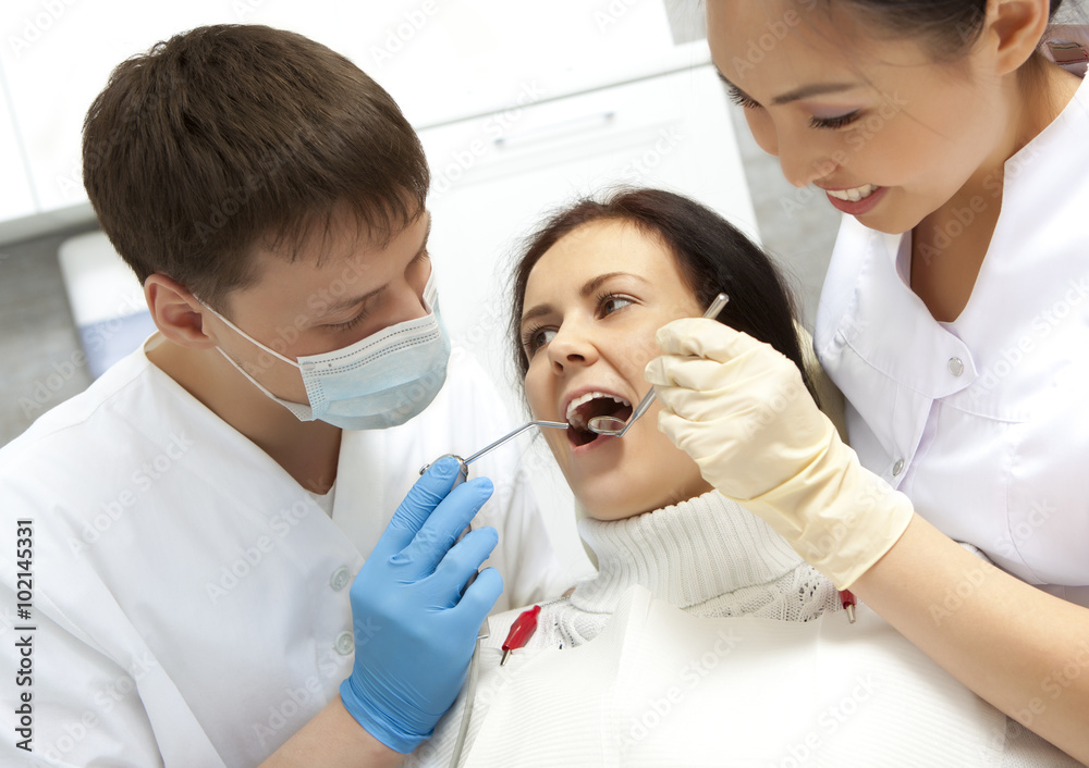Fototapeta premium Young woman keeping her mouth open while dentist examining it
