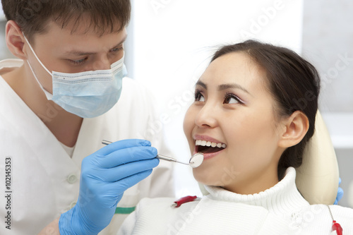 Young woman keeping her mouth open while dentist examining it