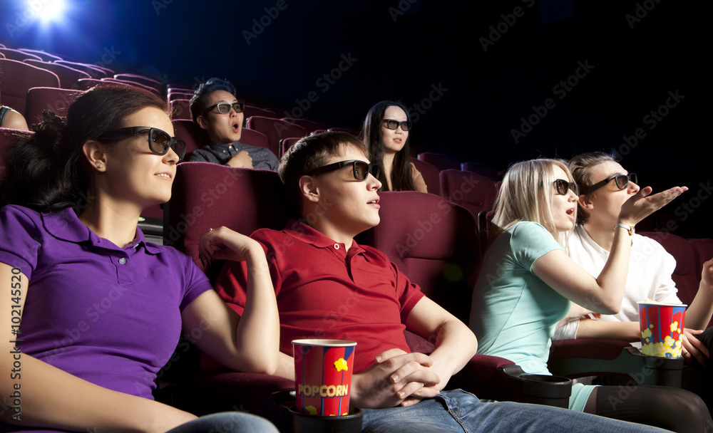 Obraz premium Young people sitting at the cinema, watching a film