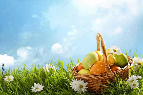 Obraz na płótnie Basket of easter eggs on green grass w salonie