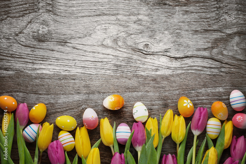Tulips and easter eggs on wood background