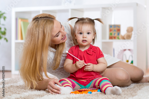 Mother is showing child how to play xylophone toy