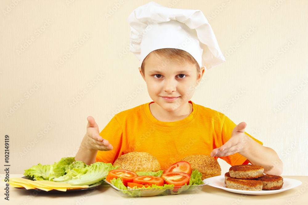 Little funny chef at the table with ingredients for a hamburger
