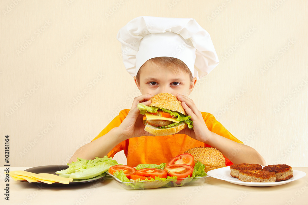 Little funny chef is tasting the cooked hamburger Little funny chef is tasting the cooked hamburger