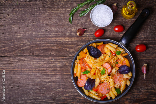 pasta with sausage, peppers, cheese and herbs on a wooden background