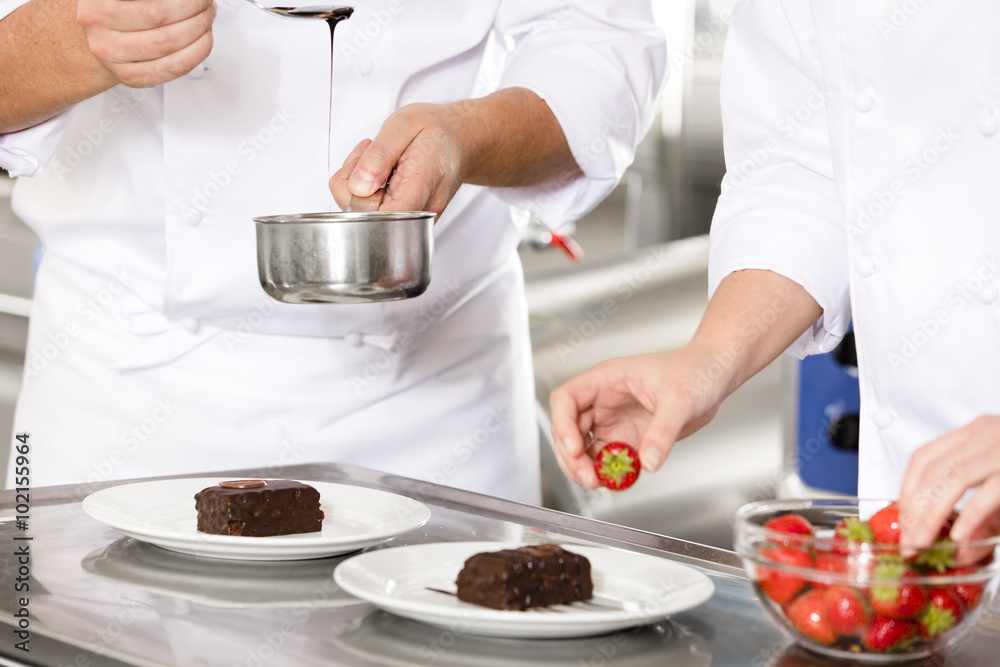 Chef decorates dessert cake with chocolate sauce in kitchen Chef decorates dessert cake with chocolate sauce in kitchen