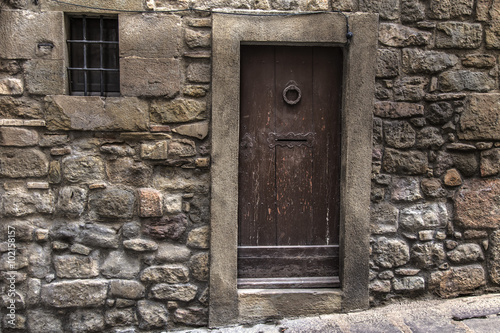 Closed medieval door on a stone rock wall facade