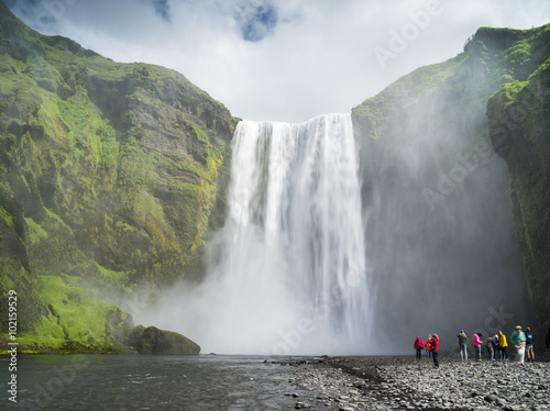 people shooting on the camera under big waterfall in Iceland