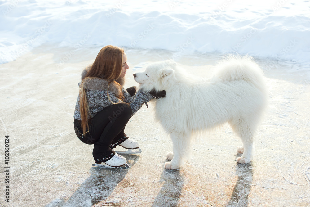Φωτογραφία young Figure skating woman with dog Samoyed at the frozen lake in the winter