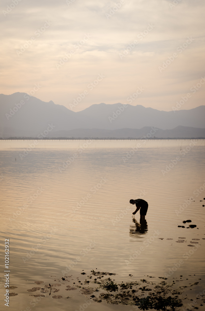 silhouette of a fisherman in the river at sunset silhouette of a fisherman in the river at sunset